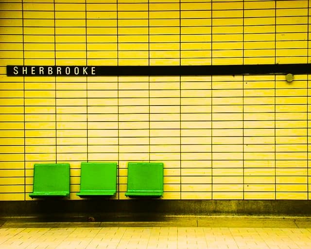 A metro station — green seats against a yellow-tiled wall beneath a “Sherbrooke” sign